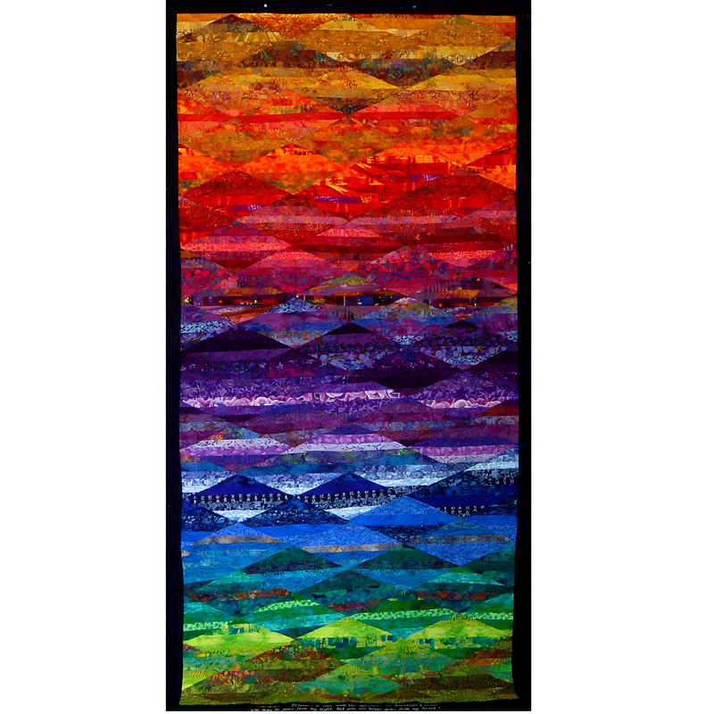 Tall rectangular quilt by Rosie Rhine of Rhino Quilting with a black border, pieced from horizontal strips of fabric in rainbow colors. From top to bottom, the colors move from gold and orange through bright red, deep purple, and violet, then to blue, teal, green, and lime. Overlapping diamond and wave shapes in each band form winding pathways that cross the quilt.
