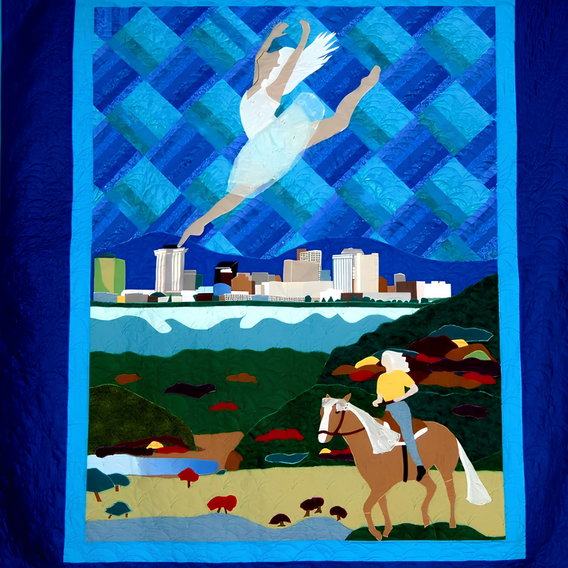 Pictorial art quilt by Rosie Rhine of Rhino Quilting with a deep blue border and a bright blue inner frame. At the top, a ballerina in a pale, sheer dress leaps with her arms raised against a blue lattice of woven-looking diamond shapes. In the middle, a city skyline sits along a band of light blue water. At the bottom, a gray-haired woman in a yellow shirt rides a palomino horse through green and olive hills dotted with red trees, with a small blue pond at the lower left.