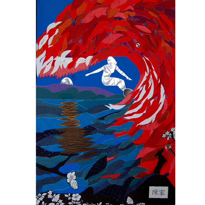 Bereavement quilt by Rosie Rhine of Rhino Quilting showing a surfer in white and silver fabric riding a large curling wave made of overlapping red and white leaf-shaped pieces. The wave arches over a deep blue sky with a pale moon. Below it, layers of teal, green, blue, and purple fabric form the sea and distant hills, with a glowing orange reflection on the water. Black fabric with white tropical flowers and leaves fills the bottom edge, and a small label with Chinese characters sits in the lower right corner.