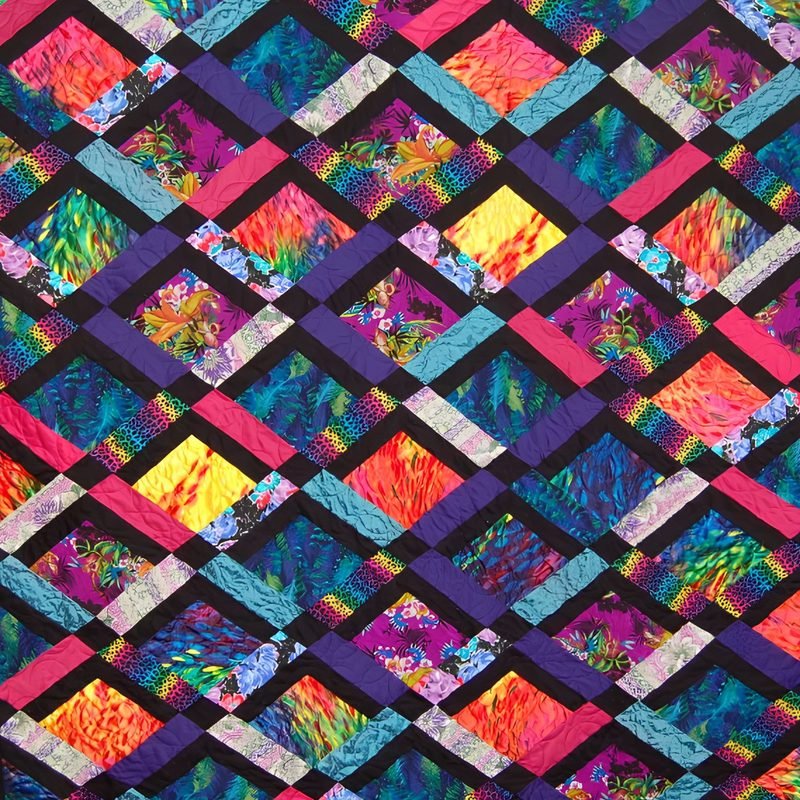 Close-up of a quilt by Rosie Rhine of Rhino Quilting with a diagonal lattice of black, purple, teal, and pink strips. Within the lattice, square windows of vivid fabrics in magenta, orange, yellow, turquoise, and green show feather and abstract patterns. Short pieced strips of rainbow prints and pale gray fabric add accents at the corners of the squares, and quilting stitches curve across the surface.